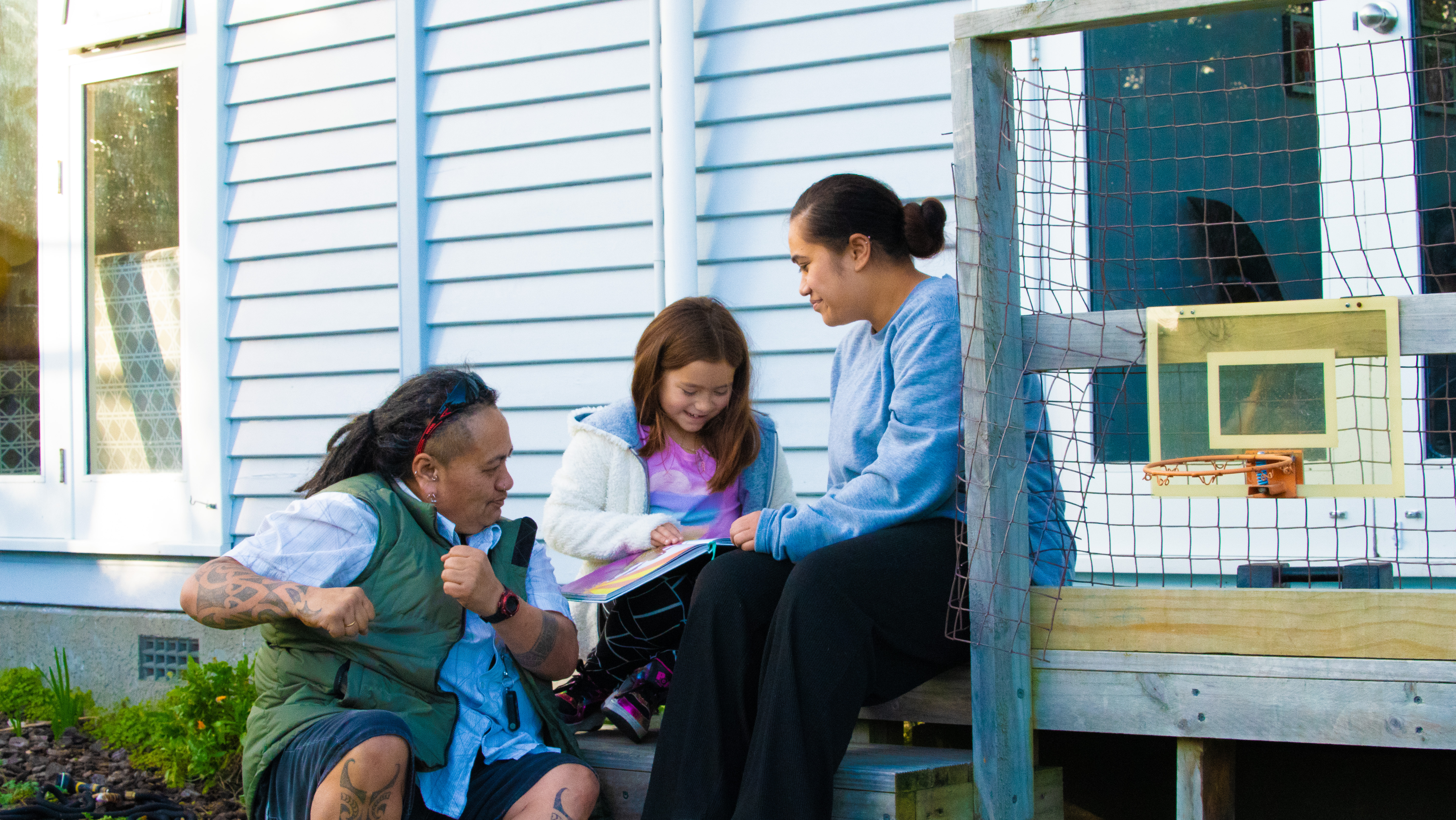 Whānau reading on the back deck 2