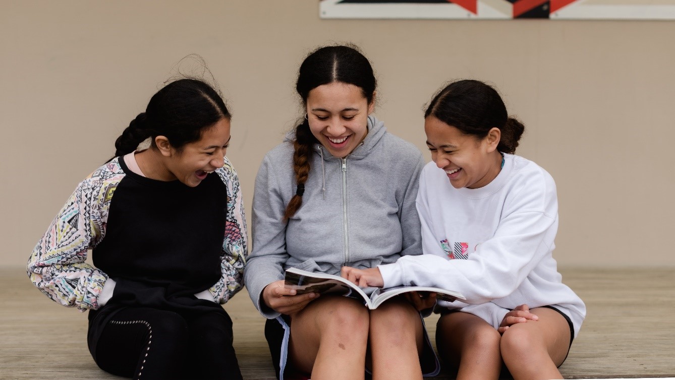 Three teen girls reading and laughing