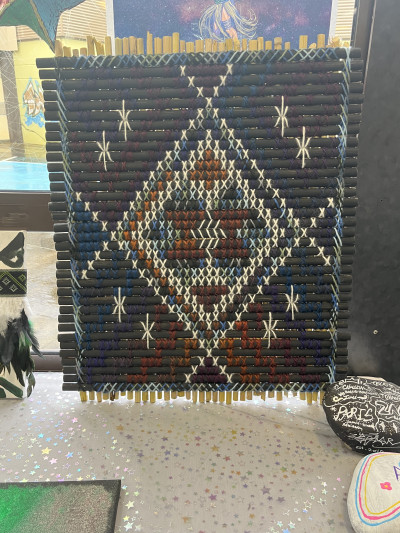 A traditional Māori woven panel with a diamond style pattern and white stars to represent Matariki.