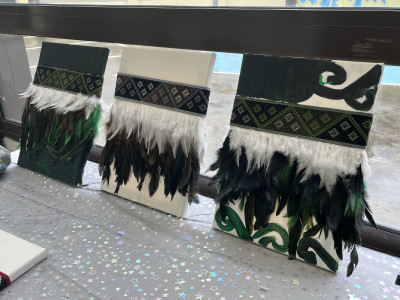 Three Maori weavings made on canvas using feathers and paint.